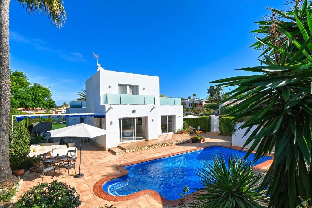 a villa with a swimming pool in front of a house at Reina in Jávea