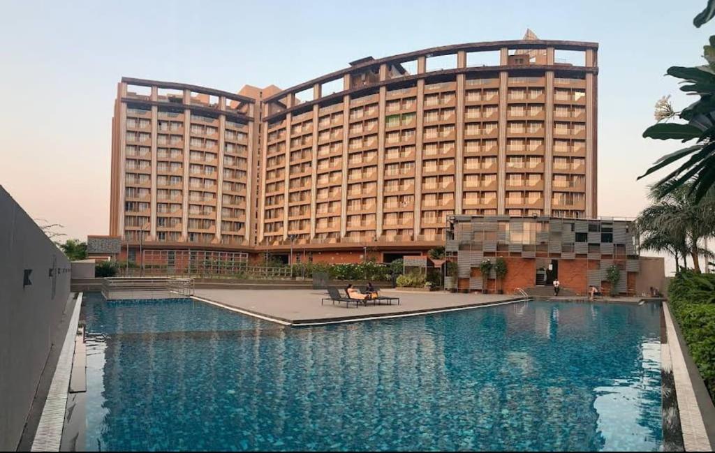 a hotel with a swimming pool in front of a building at Studio Flat Near Airport in Surat