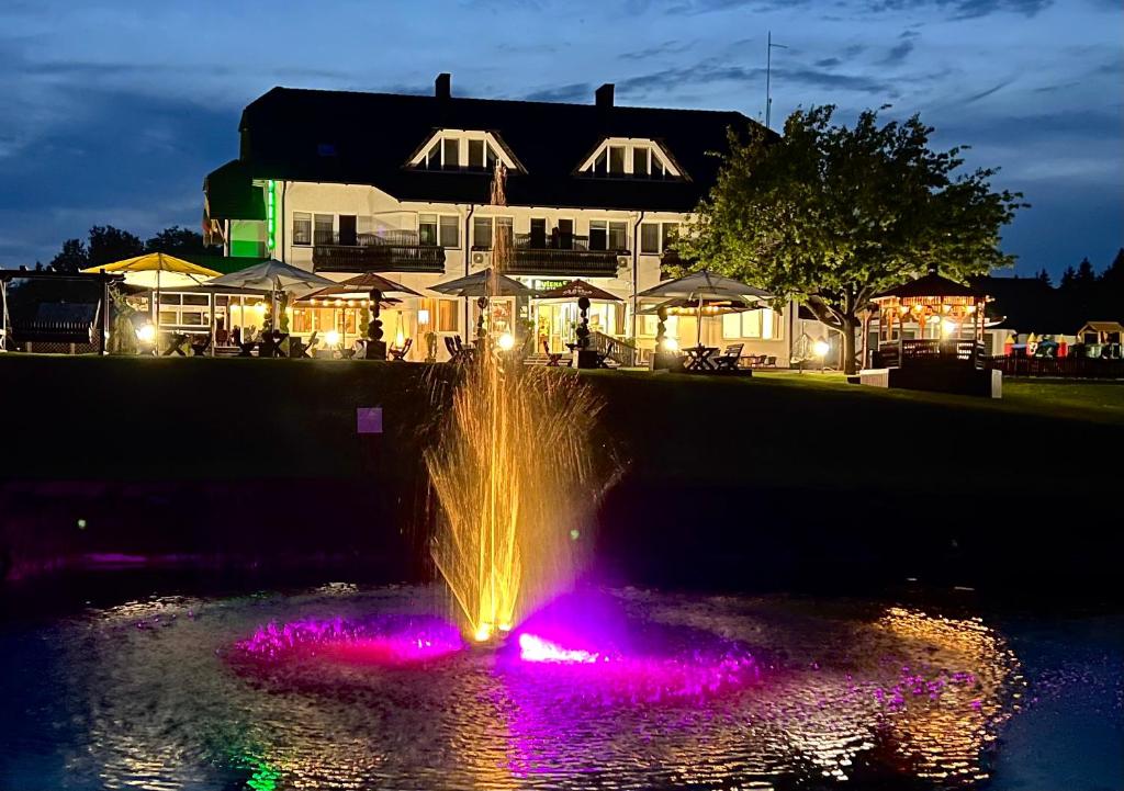 a fountain in the water in front of a building at Butenas Hotel Tyla in Biržai