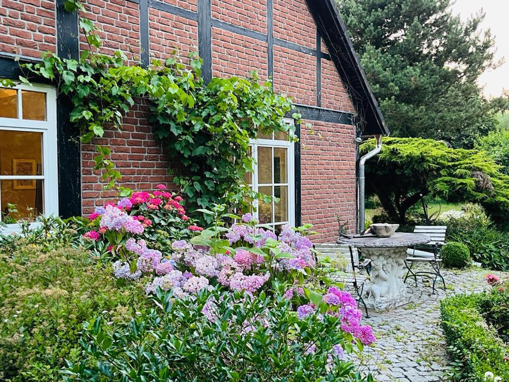 a garden with a table and flowers in front of a brick building at Landhaus Köhn in Giekau
