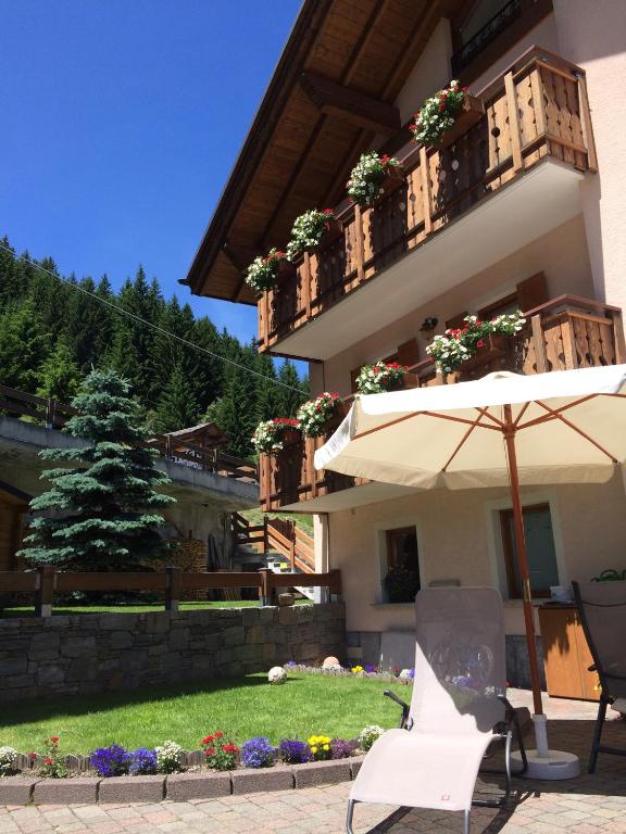 an umbrella and a chair in front of a building at Casa Lucia in Valdidentro