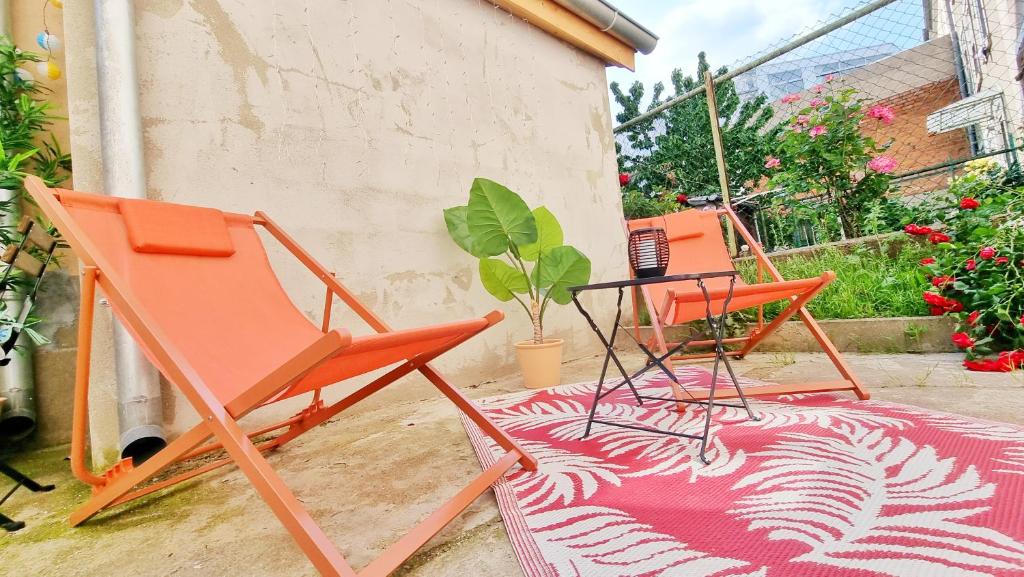 2 chaises orange et une table sur un tapis dans l'établissement Le Ptit Paradis - Calme - Wifi - Cour privée - Relax BNB, à Mulhouse