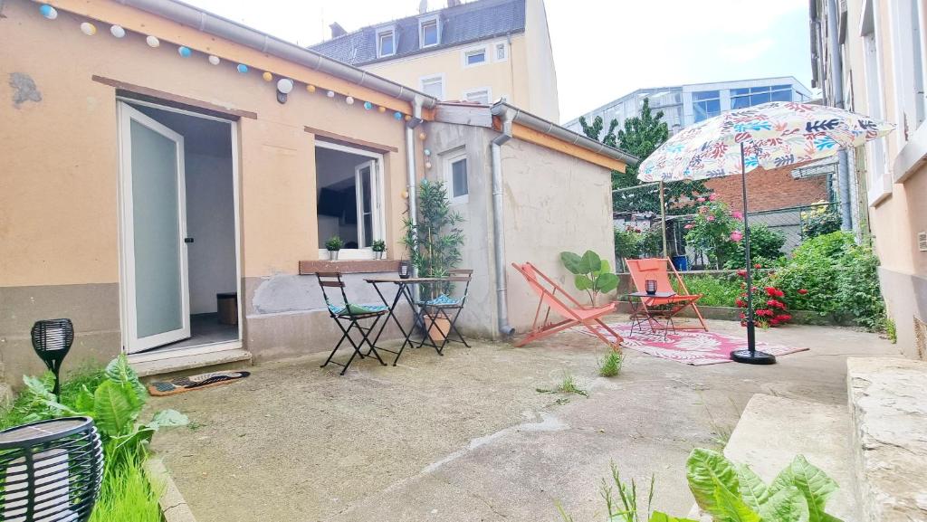 a patio with a table and chairs and an umbrella at Le Ptit Paradis - Calme - Wifi - Cour privée - Relax BNB in Mulhouse