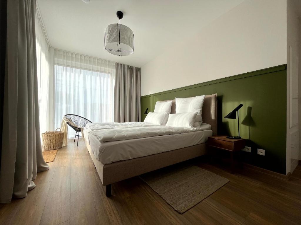 1 dormitorio con 1 cama grande y pared verde en MOKA Living eWald - 2Zi Apartment-FeWo, E-Charger, Barrierearm, Boxspring, TV en Borkheide