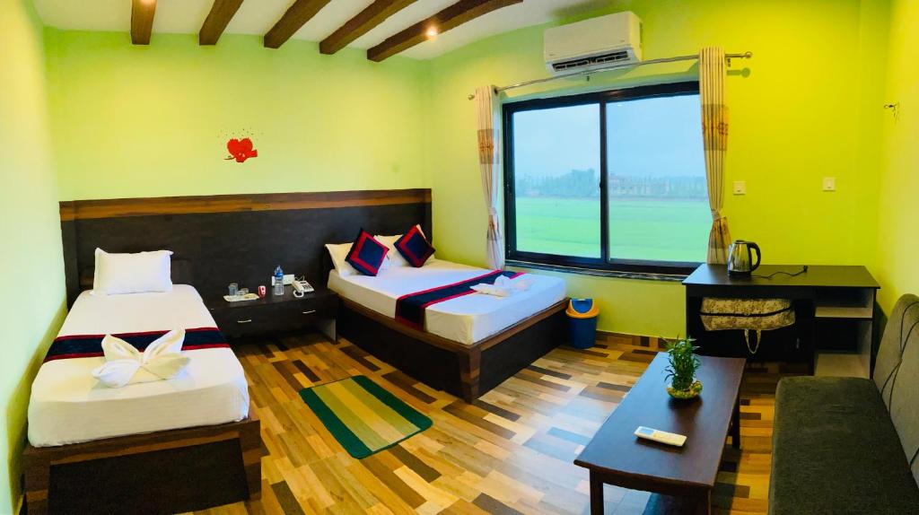 Cette chambre comprend deux lits, un canapé et une fenêtre. dans l'établissement The Lumbini Hotel, à Rummindei