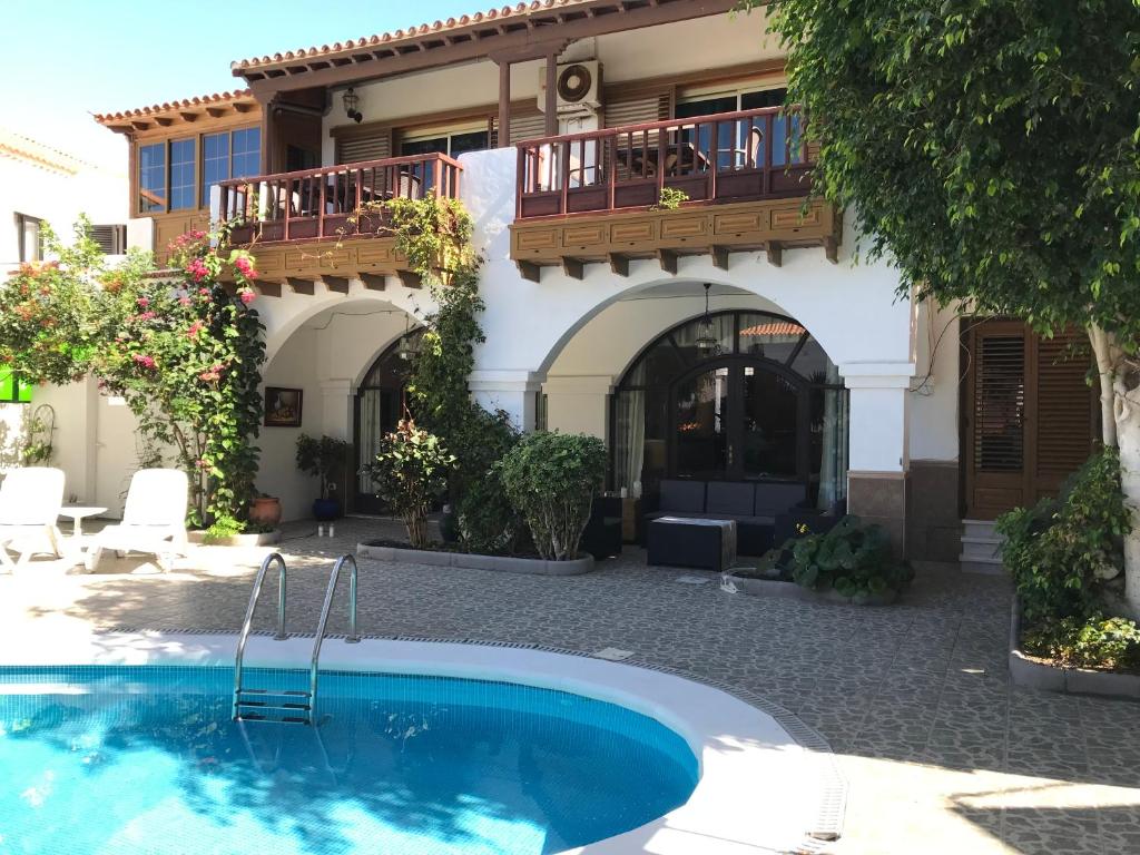 a house with a swimming pool in front of a building at Las Americas Family Inn in Playa de las Americas