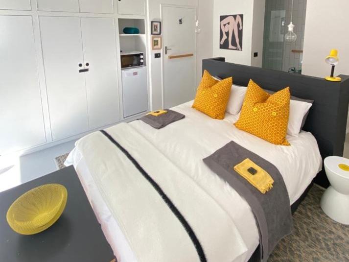 a bedroom with a large bed with yellow pillows at Yellow Door Hermanus in Hermanus