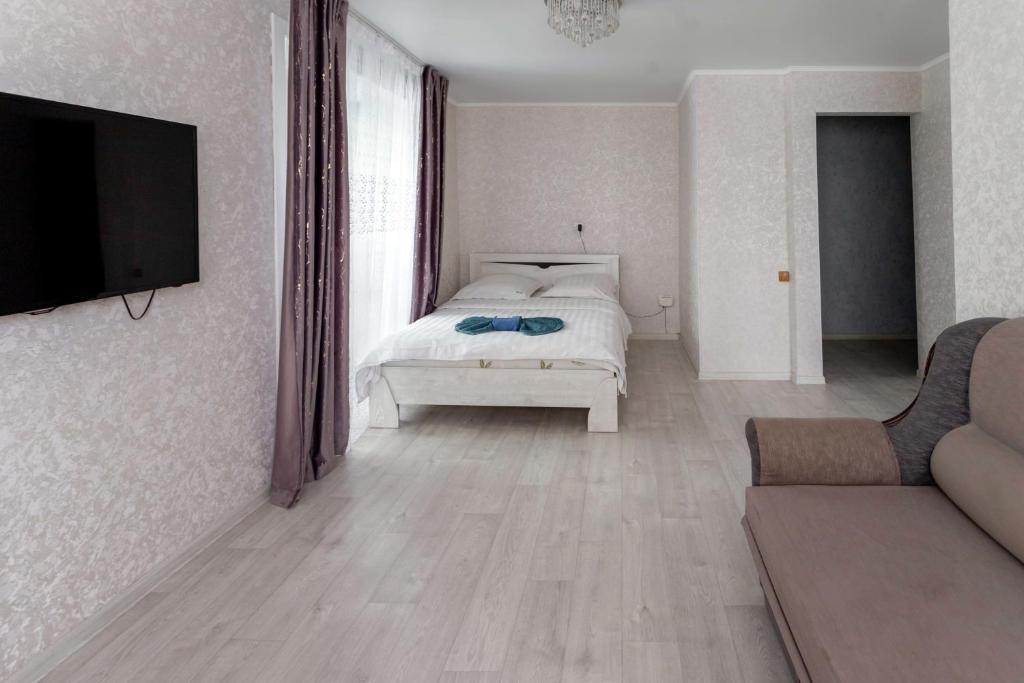 1 dormitorio con 1 cama, TV y sofá en Альпина en Petropavlovsk
