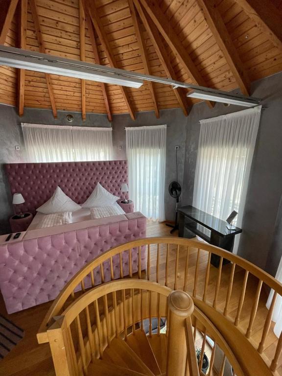 a bedroom with a pink bed and a wooden staircase at Auszeit am Dankernsee in Haren