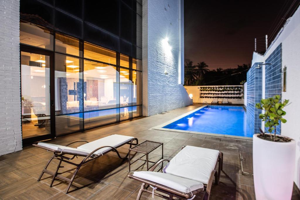 a patio with two chairs and a swimming pool at Hotel de Luxo Tango Suites & Coworking Cumbuco in Cumbuco