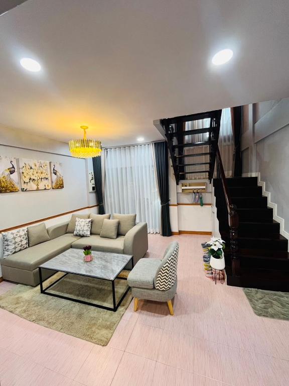 a living room with a couch and a table and stairs at KITJA MY HOME in Hat Yai