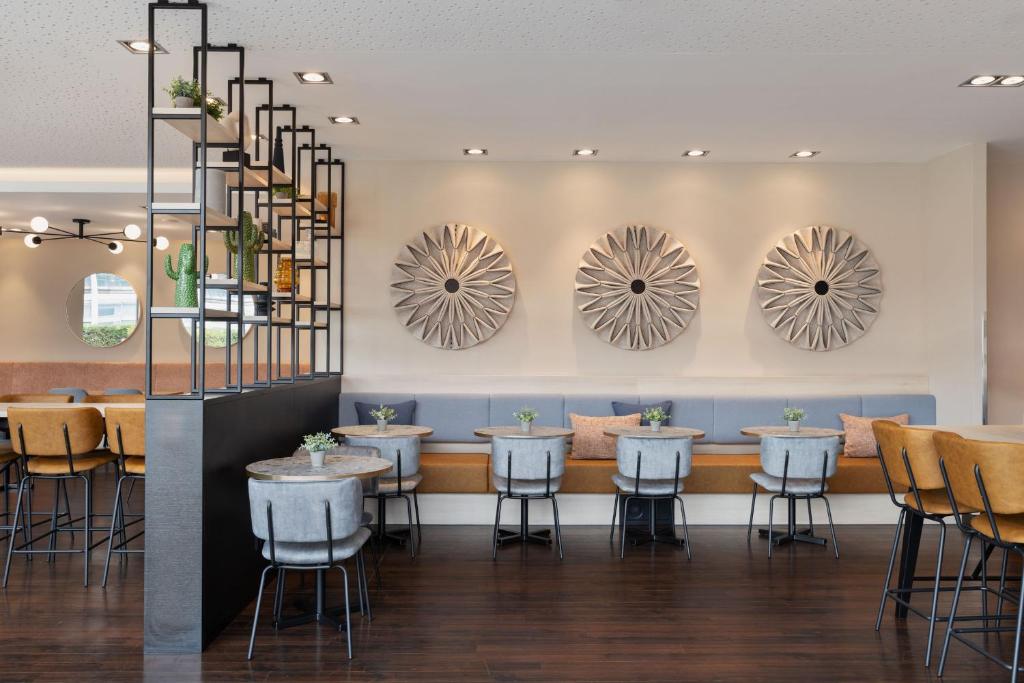 um restaurante com mesas, cadeiras e espelhos em Courtyard by Marriott Linz em Linz