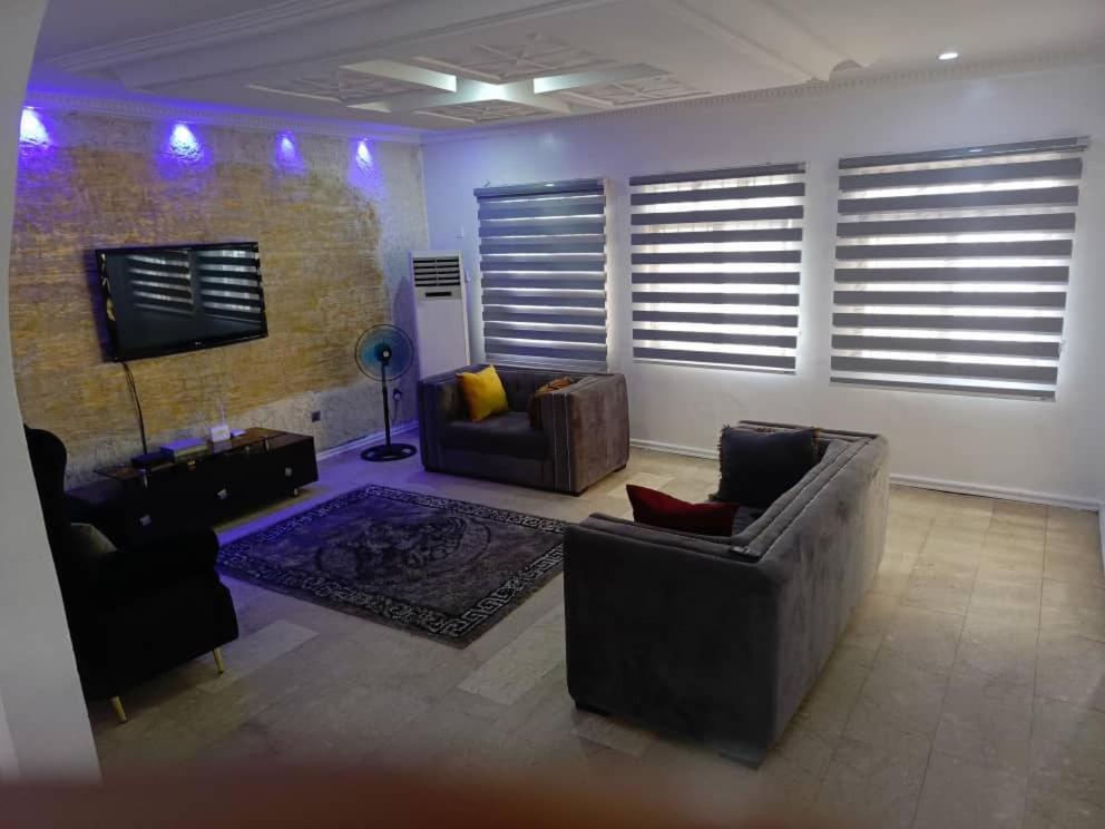 sala de estar con 2 sofás y TV en DND Apartments, en Benin City