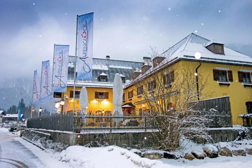 Un edificio amarillo con carteles en la nieve. en DEVA Hotel Alpenglück, en Weißbach