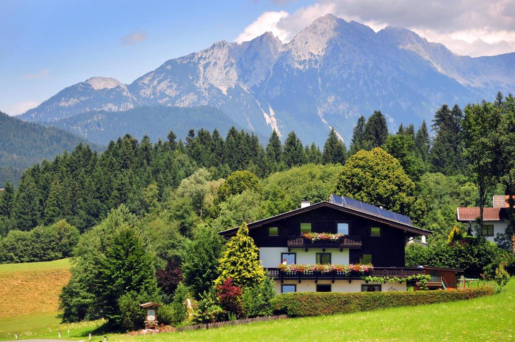 a house in a field with mountains in the background at Gästehaus Hölzl in Itter