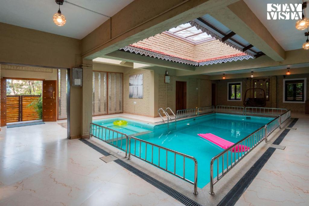 a large indoor swimming pool with a large window at Otonia by StayVista with Indoor swimming pool, Modern interiors & a mix of indoor & outdoor games in Panchgani