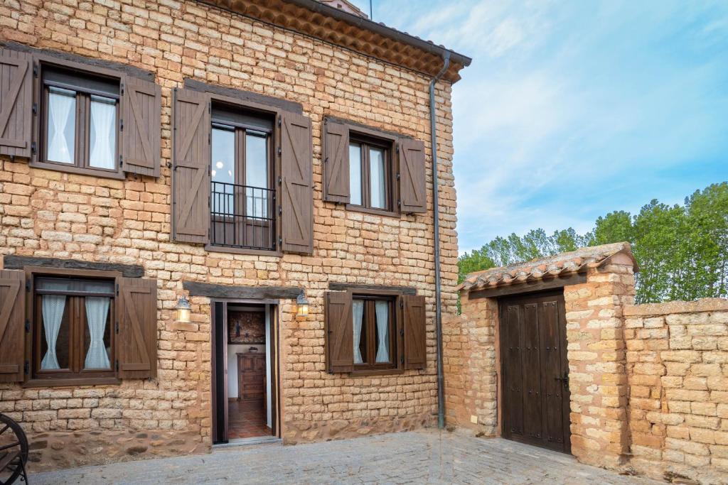 ein Backsteingebäude mit Holztüren und Fenstern in der Unterkunft Casa Rural Adolfo in Santa Inés