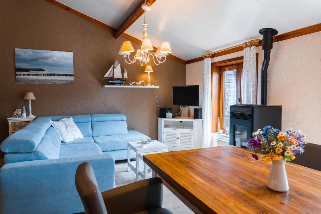 uma sala de estar com um sofá azul e uma mesa de madeira em Village Park P25 em De Haan