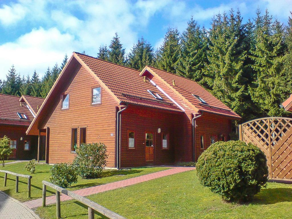 ein rotes Haus mit einem Zaun davor in der Unterkunft Naturerlebnisdorf Blauvogel 6 in Hasselfelde