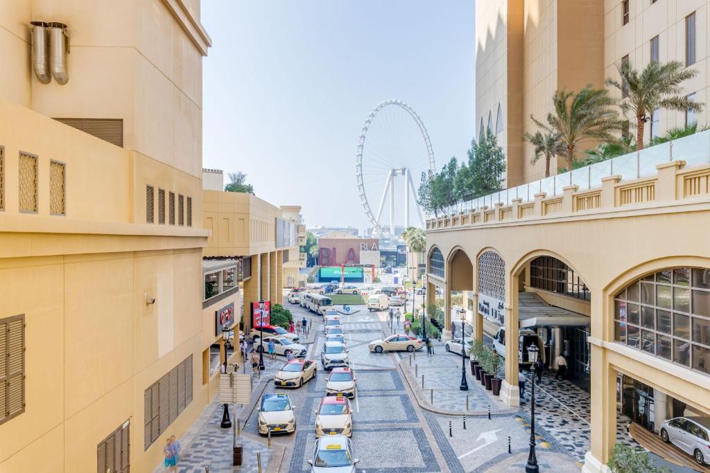 a city street with cars and a ferris wheel in the background at GLOBALSTAY. Modern Apartments steps to JBR Beach in Dubai