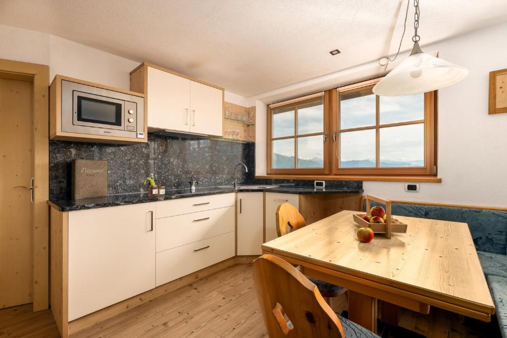 eine Küche mit einem Holztisch und einer Mikrowelle in der Unterkunft Pitznerhof in Meransen