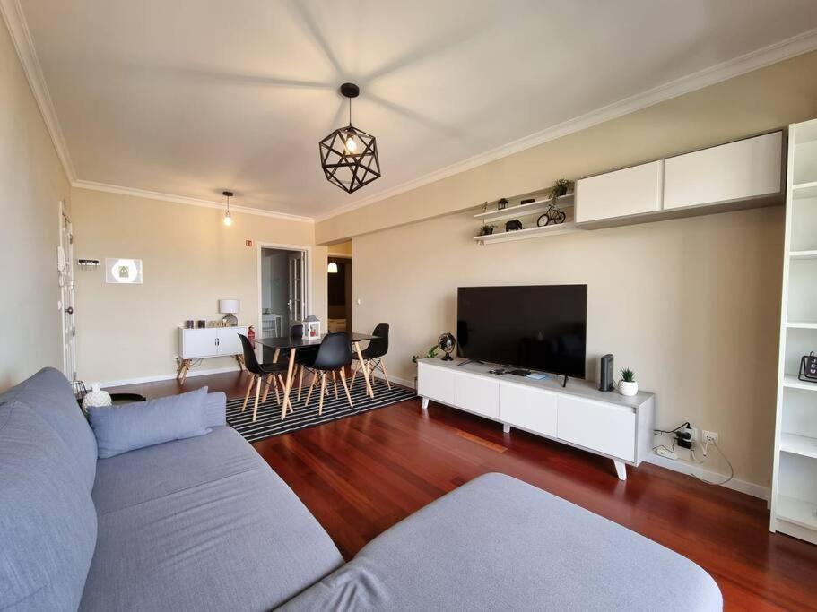 a living room with a couch and a tv at Olimpia Gardens View by Rentallido in São Gonçalo