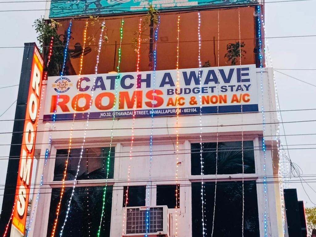 Un cartello sul lato di un edificio con le luci di Natale di CATCH A WAVE BUDGET STAY a Mamallapuram