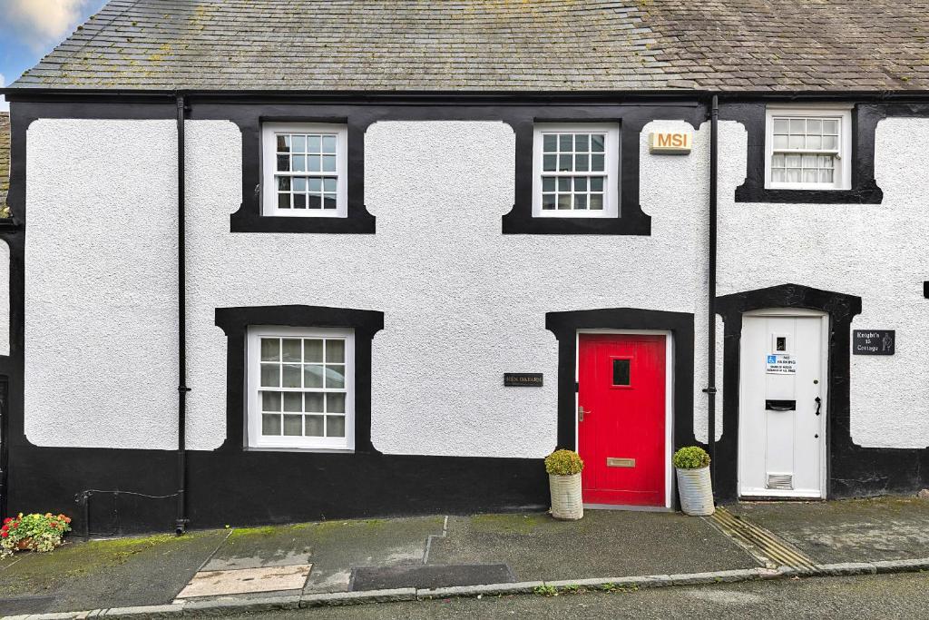 a black and white house with a red door at Finest Retreats - Hen Dafarn in Conwy
