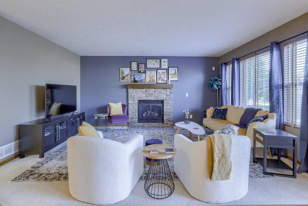 a living room with two white chairs and a fireplace at Cozy Winter Retreat with Modern Minimalist Charm in Omaha