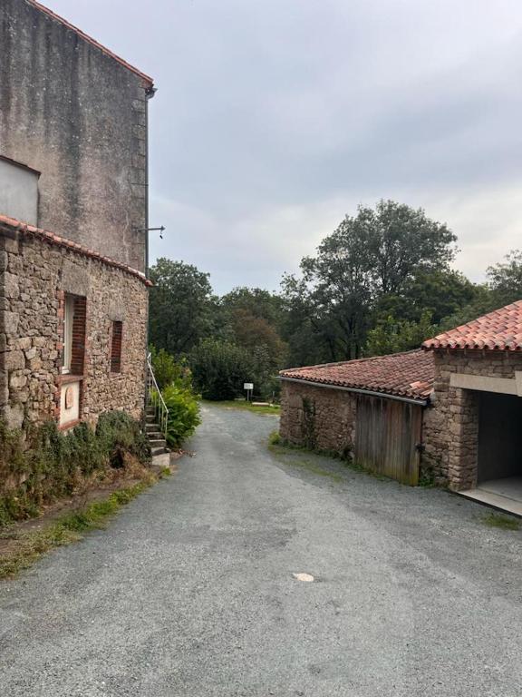 an empty road next to an old stone building at Gîte les Pieds dans l&#39;eau bord de Sèvre, 10 min du Puy du Fo in Treize-Vents
