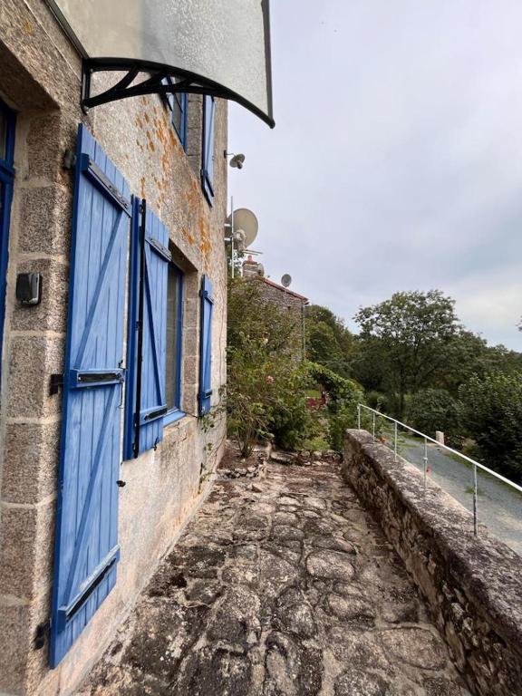 a building with a blue door and a stone walkway at Gîte les Pieds dans l&#39;eau bord de Sèvre, 10 min du Puy du Fo in Treize-Vents
