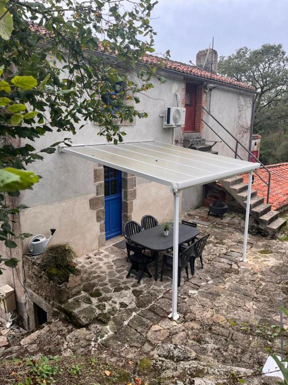 a patio with a table and chairs under a white umbrella at Gîte les Pieds dans l&#39;eau bord de Sèvre, 10 min du Puy du Fo in Treize-Vents