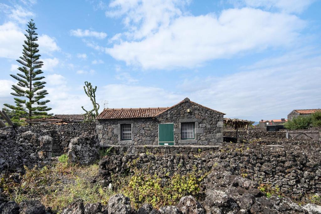 uma casa de pedra com uma porta verde numa parede de pedra em Adega Maciel em Lajido