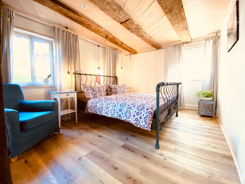 een slaapkamer met een bed en een blauwe stoel bij Ganze Wohnung - Erdgeschoss - sehr ruhig - Hundefreundlich - Regendusche - Bodenheizung - Küche - easy Check-in mit Schlüsselbox in Nehren