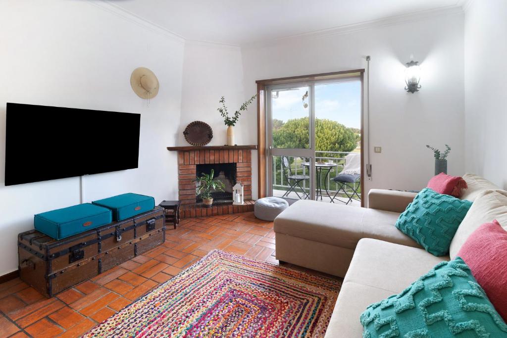 a living room with a couch and a flat screen tv at Retro Beach House Moledo in Moledo