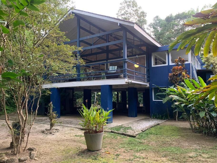a blue house with a balcony in a yard at Schönes Haus direkt am Fluß in der Mata Atlantica in São Sebastião