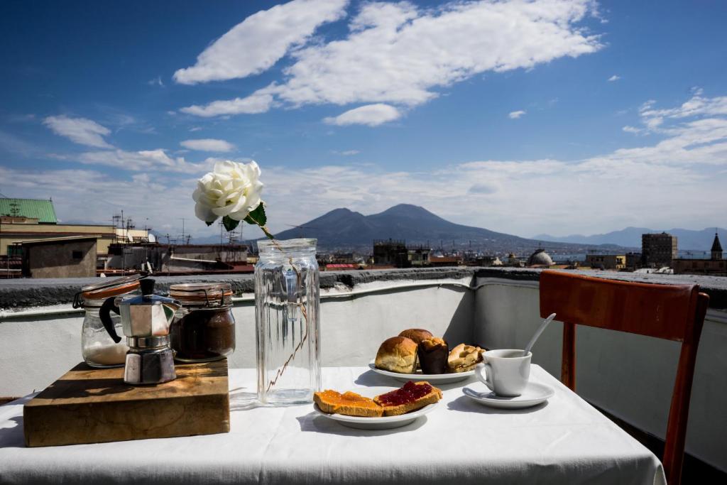 una mesa con dos platos de comida y un jarrón de flores en Taggarb, en Nápoles
