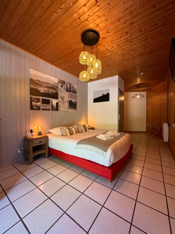 a bedroom with a large bed and a wooden ceiling at Logis Le Chalet in Saint-Maurice-en-Trièves