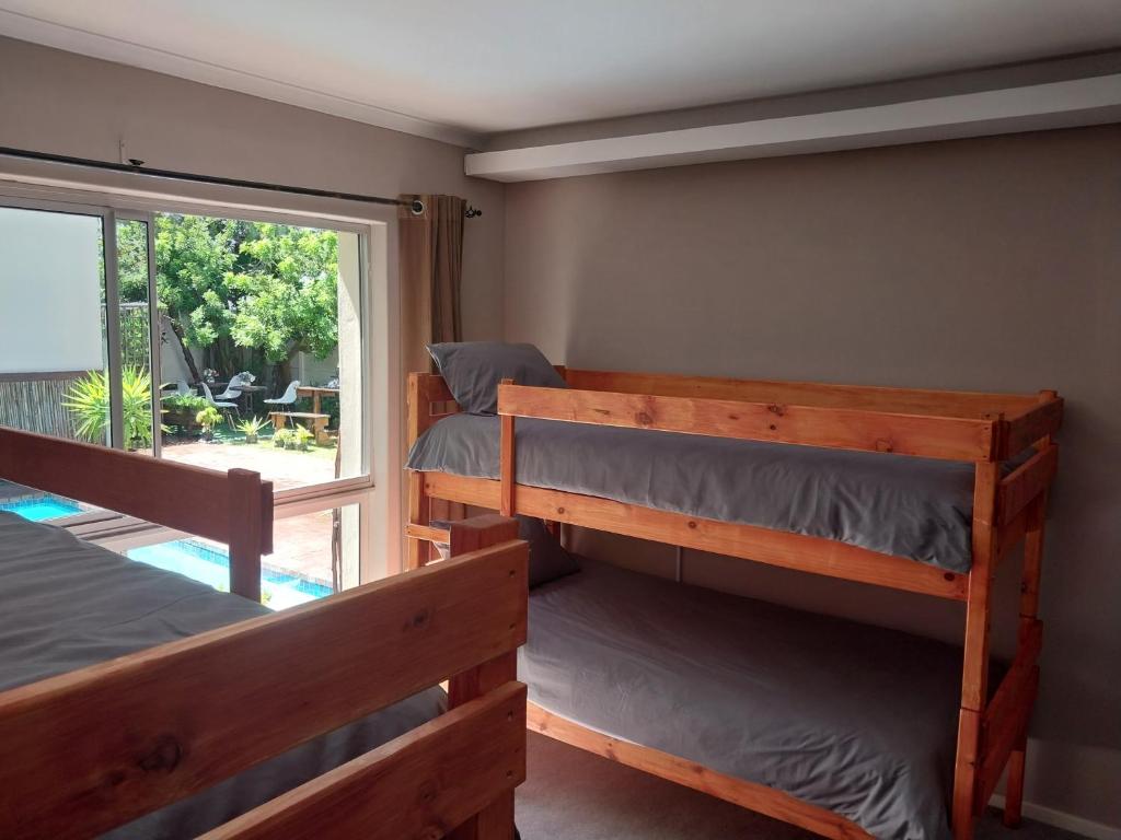 a room with three bunk beds and a window at Serenity Shores Backpackers in Cape Town