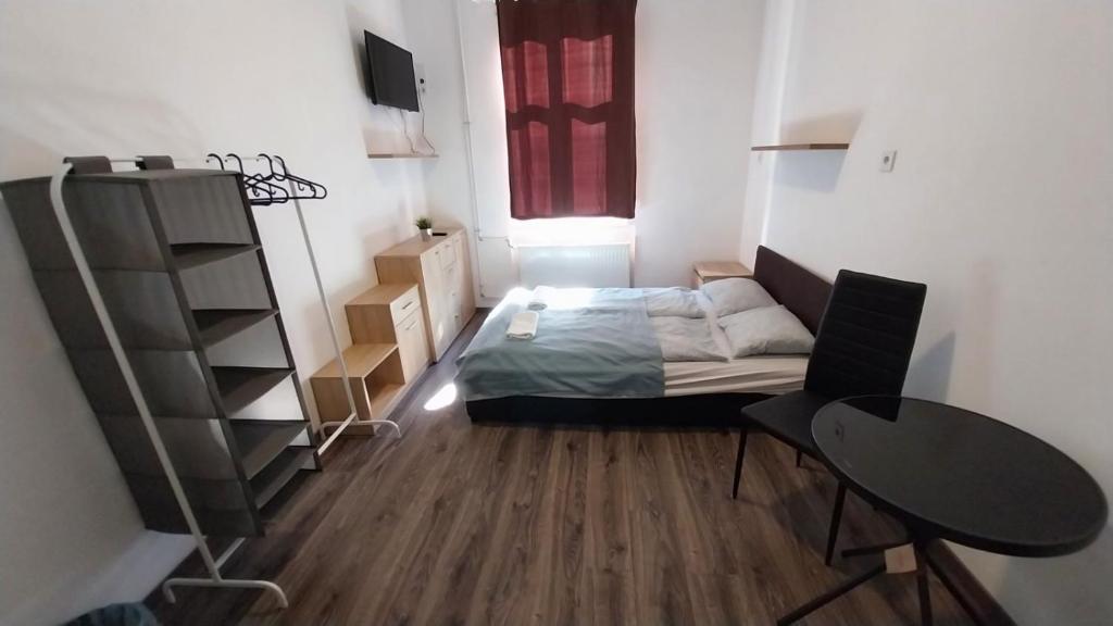 um pequeno quarto com uma cama, uma secretária e uma mesa em Aradi Rooms with Private bathroom em Budapeste