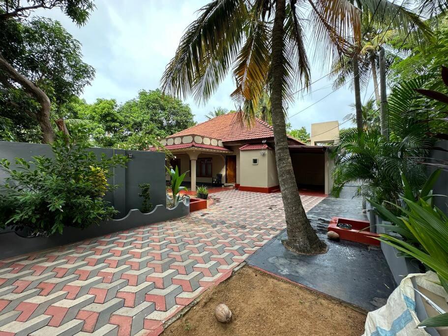 uma casa com uma palmeira e uma entrada em Villa in Kalviyankadu 
