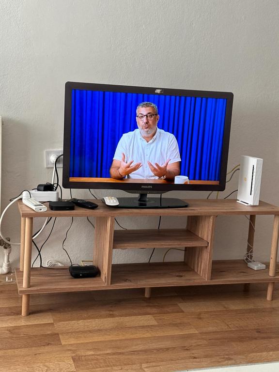 a television on a wooden stand with a man on it at Çift klimalı, 110m2, 3+1, metro 5dk, 1000mbps inte in Karşıyaka