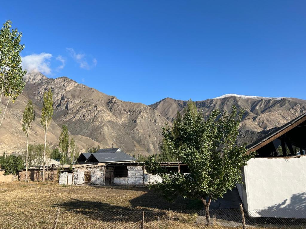 une ancienne maison dans un champ avec des montagnes en arrière-plan dans l'établissement Ata konush, à Sufi-Kurgan
