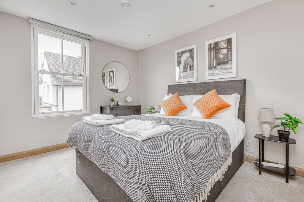 a bedroom with a large bed with orange pillows at Contemporary 2 BR apt, town centre by tent serviced apartments in Chertsey