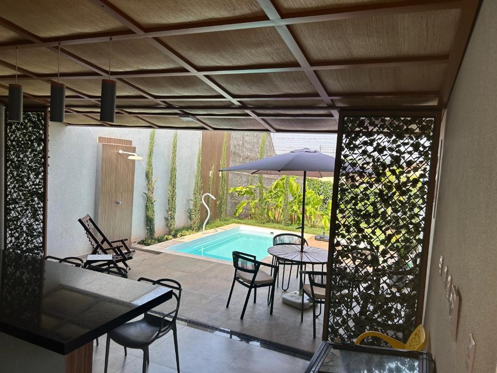 a patio with a table and chairs and a pool at Recanto Manga da Rosa - casinha de fazenda no centro da cidade in Olímpia