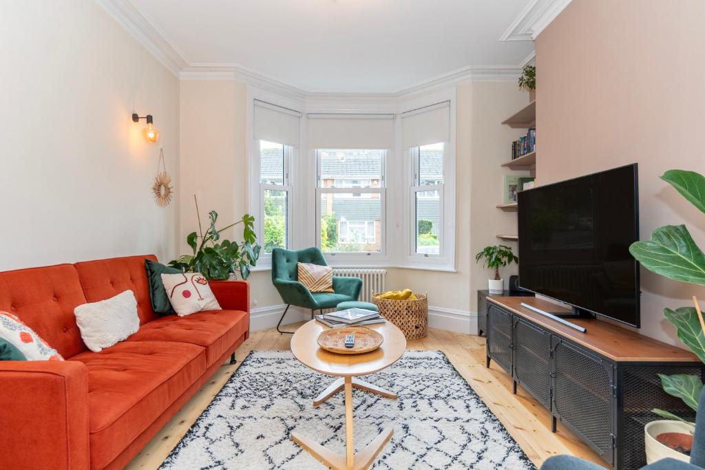 a living room with a orange couch and a flat screen tv at Chic Townhouse in the heart of Historical Exeter 5mins to Centre in Exeter