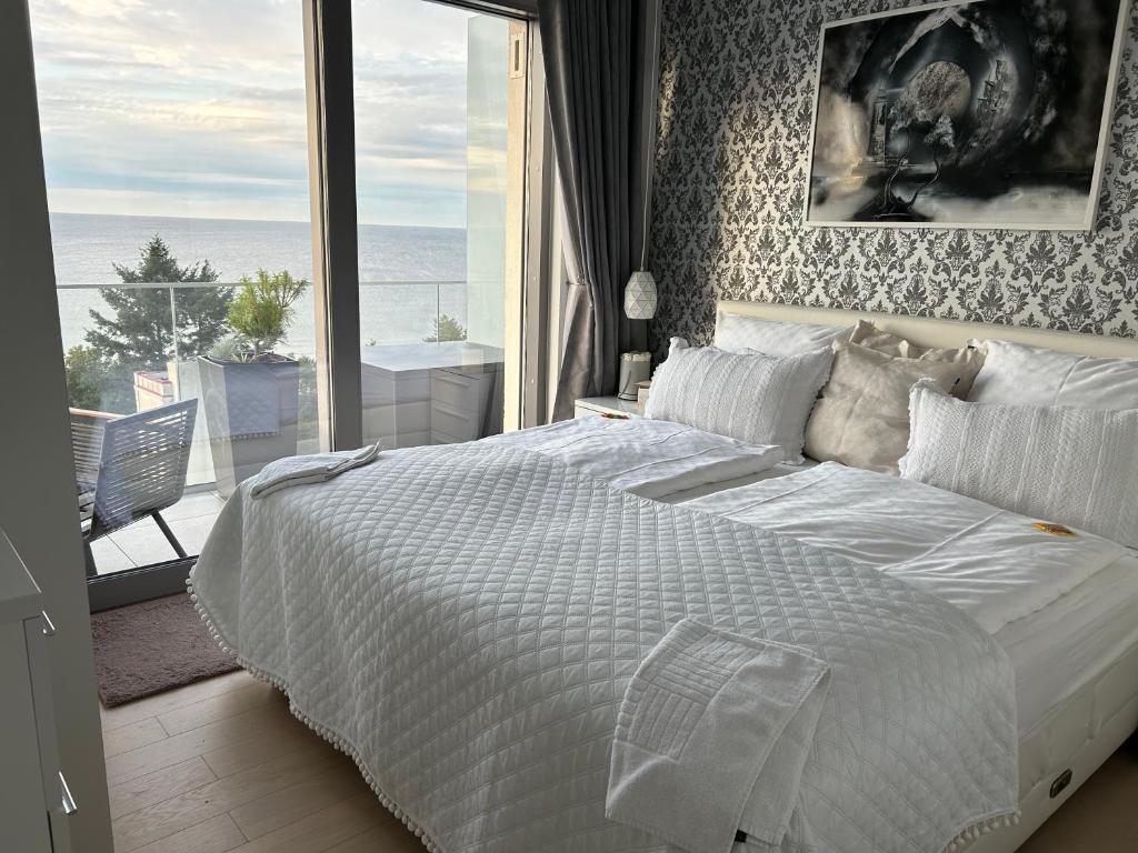 a bedroom with a large white bed and a balcony at Luxe Baltic Sunset in Międzyzdroje