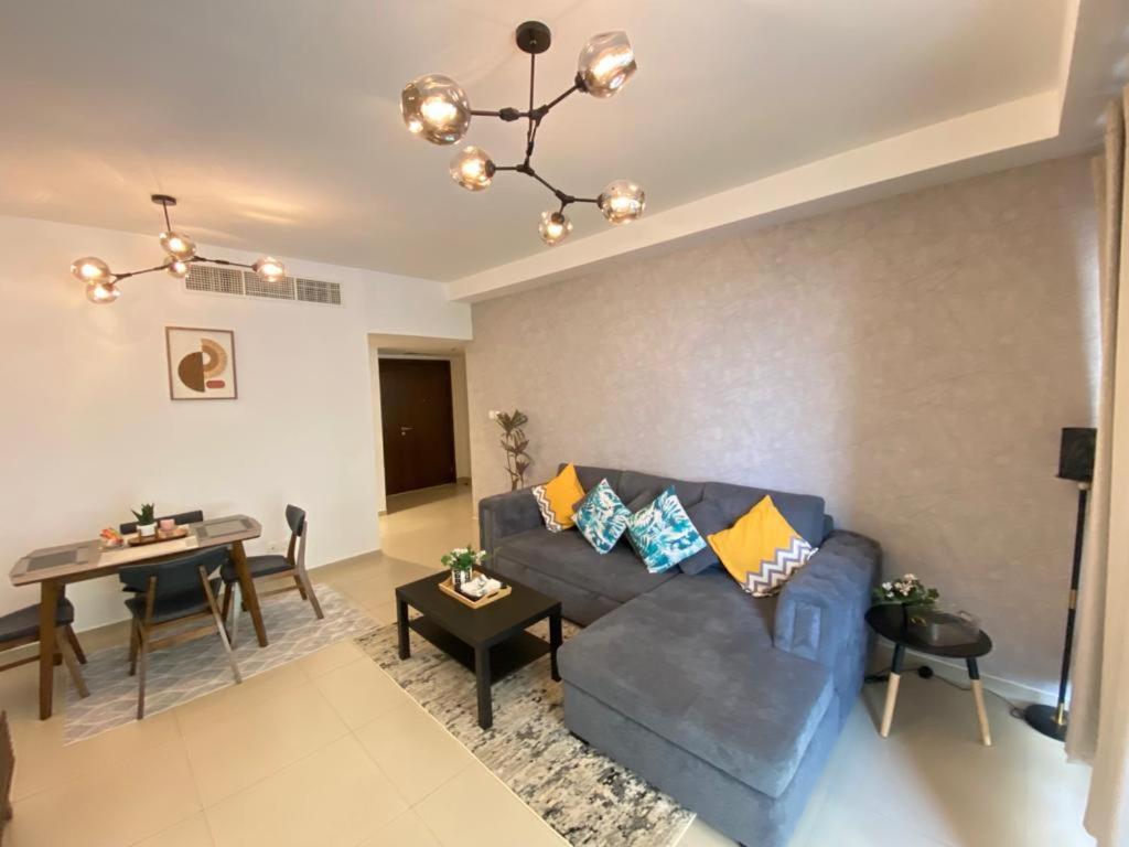 sala de estar con sofá azul y mesa en Beach Dream - a luxury 1 bedroom apartment with direct beach access en Ras al-Khaimah