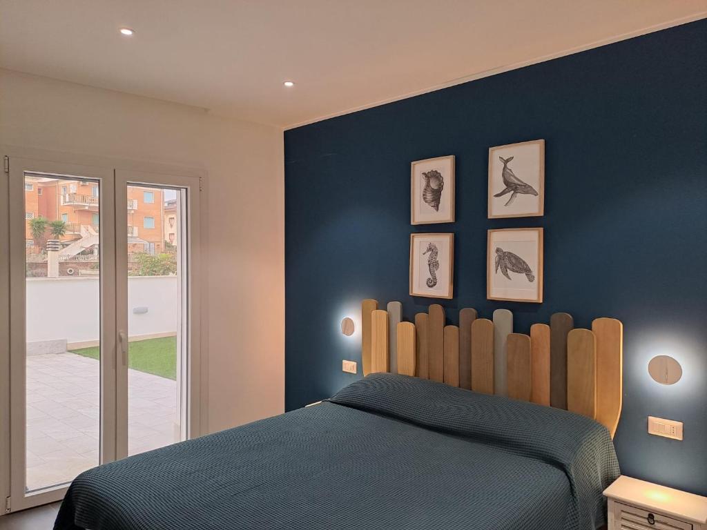 1 dormitorio con 1 cama con pared azul en Sirene452 - apartment - en Torvaianica