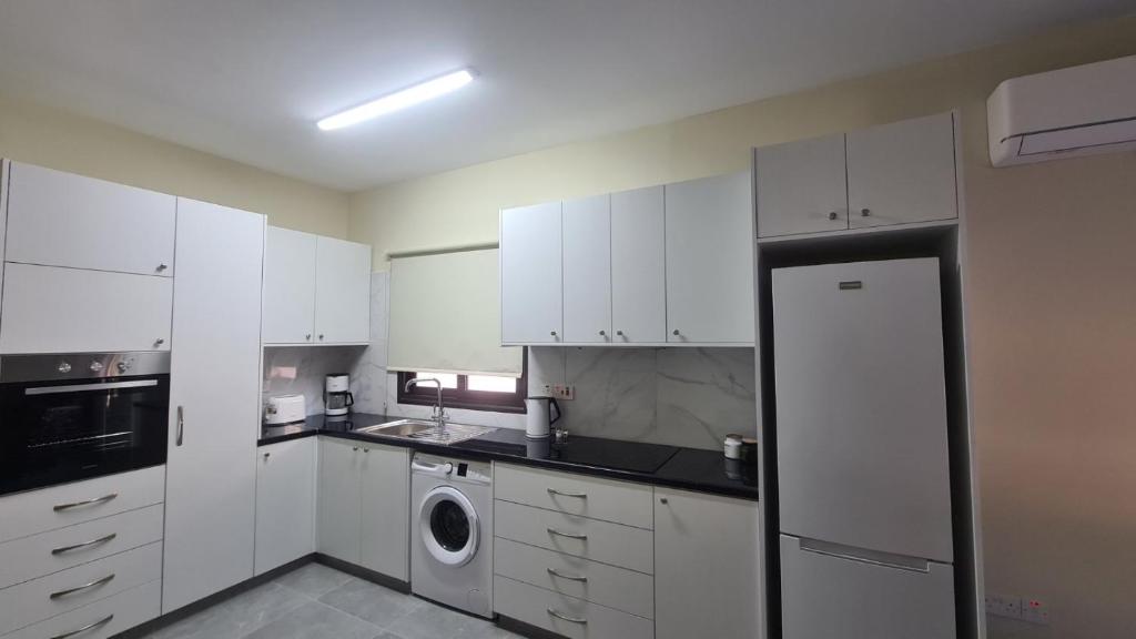 a kitchen with white cabinets and a washer and dryer at Central Two Bedroom Apartment, No 101, by IMH Travel & Tours in Paphos